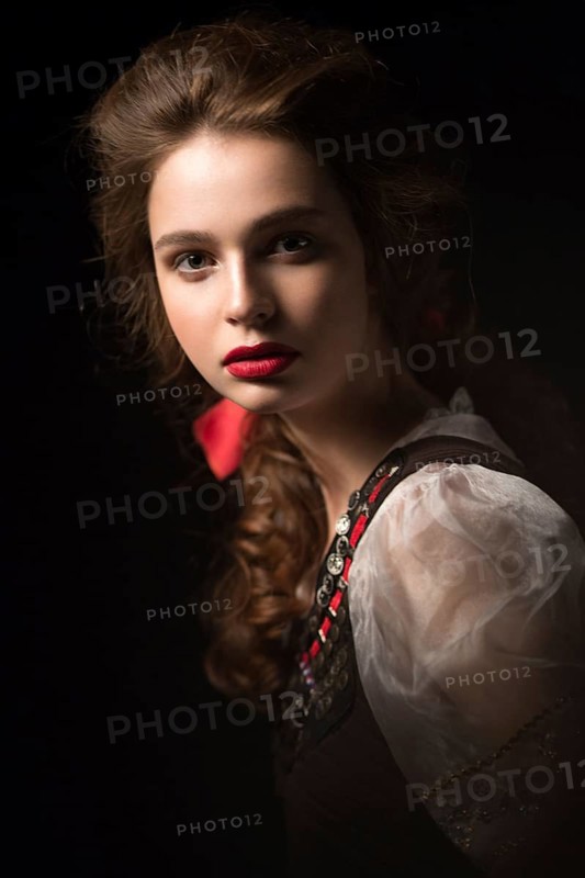 Beautiful Russian girl in national dress with a braid hairstyle and red lips. Beauty face. Picture taken in the studio on a black background