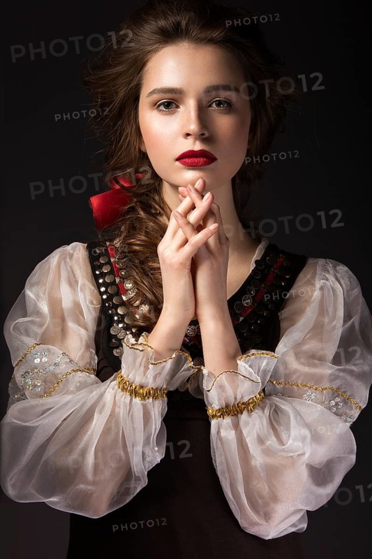 Beautiful Russian girl in national dress with a braid hairstyle and red lips. Beauty face. Picture taken in the studio on a black background