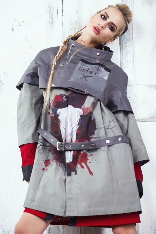 Creative unusual blond girl in designer clothes and braids on her head posing in the studio
