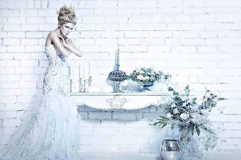 Beautiful girl in white dress in the image of the Snow Queen with a crown on her head. Picture taken in the studio with decorations