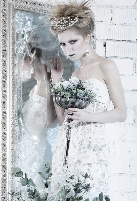 Beautiful girl in white dress in the image of the Snow Queen with a crown on her head. Picture taken in the studio with decorations