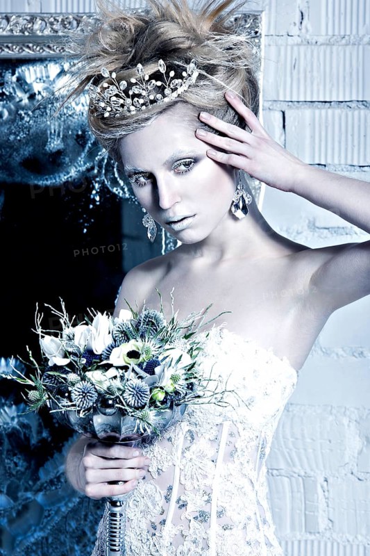 Beautiful girl in white dress in the image of the Snow Queen with a crown on her head. Picture taken in the studio with decorations