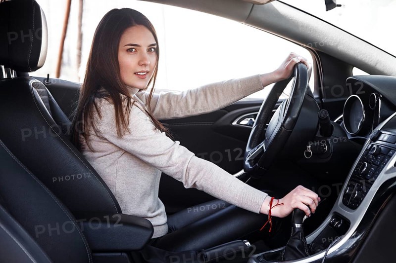 Young beautiful happy woman sitting at the wheel new car