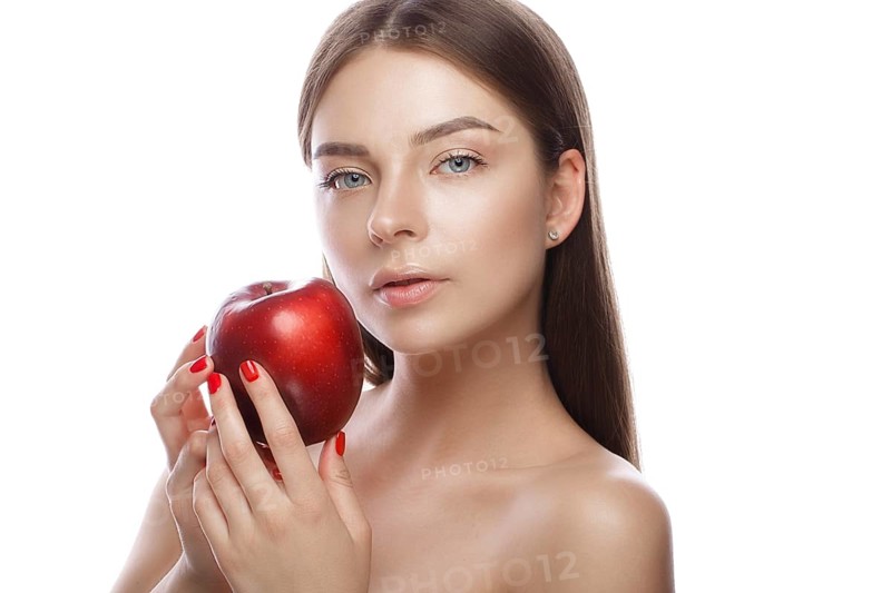 Beautiful young girl with a light natural make-up and perfect skin with apple in her hand. Beauty face. Picture taken in the studio on a white background