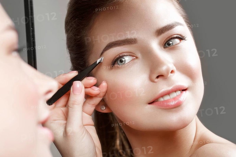Beautiful girl makes herself a make-up in the mirror. Beauty face. Photo taken in studio