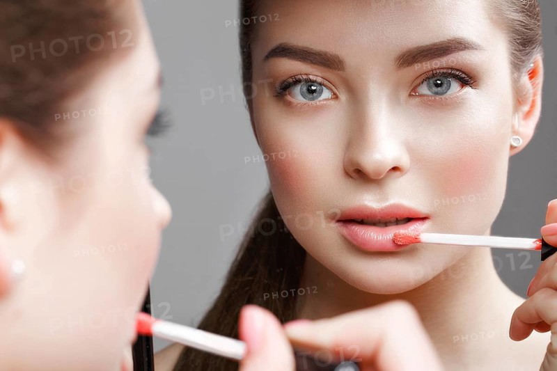 Beautiful girl makes herself a make-up in the mirror. Beauty face. Photo taken in studio