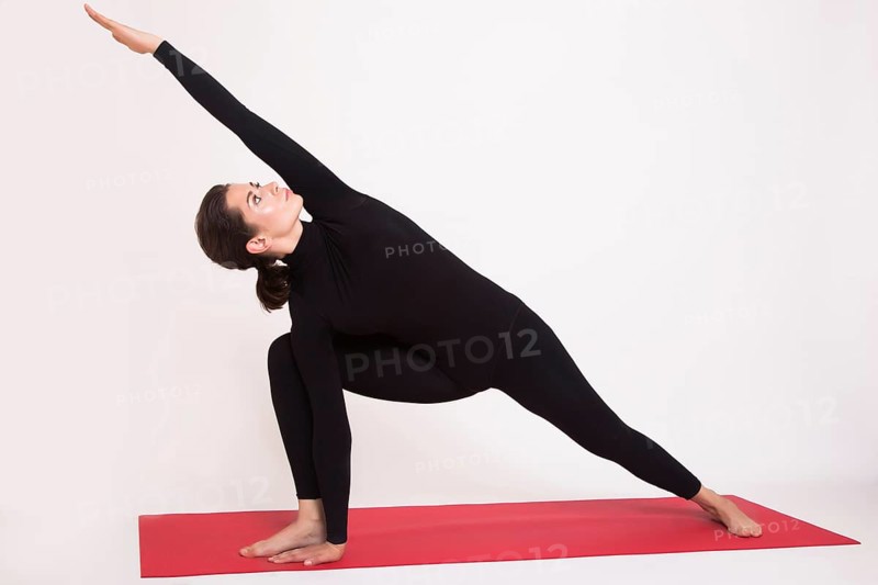 Beautiful athletic girl in black suit doing yoga asanas. Isolated on white background