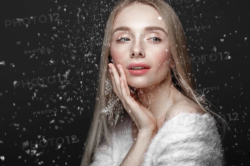 Beautiful blonde girl in a winter image with snow. Beauty face. Photo taken in the studio