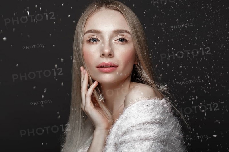 Beautiful blonde girl in a winter image with snow. Beauty face. Photo taken in the studio