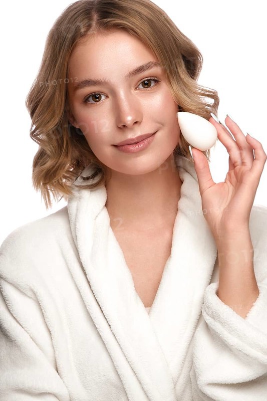 Beautiful tender young girl in a white coat with clean fresh skin posing in front of the camera. Beauty face. Skin care. Photo taken in studio on a white isolate background