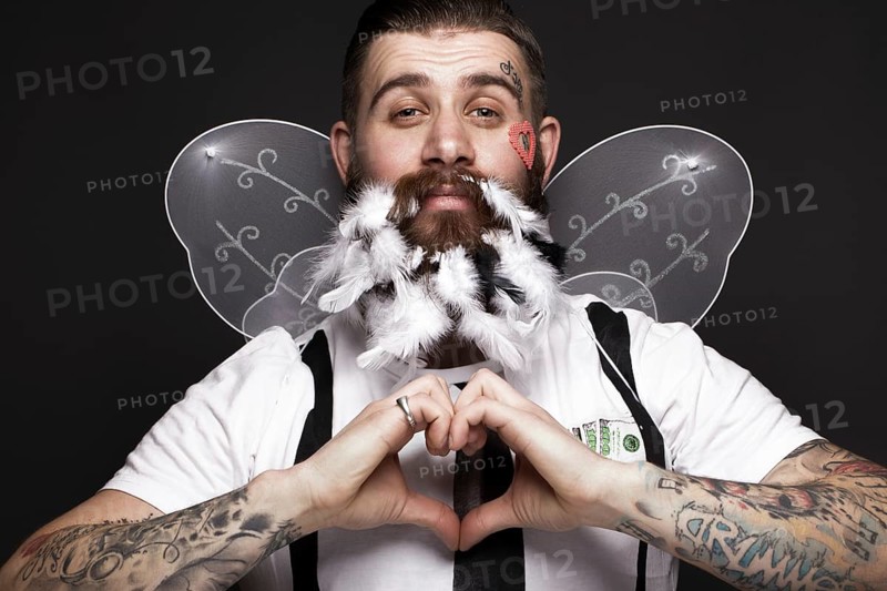 Funny bearded man with feathers and wings in the image of Cupid Valentine's Day. Portrait shot in studio