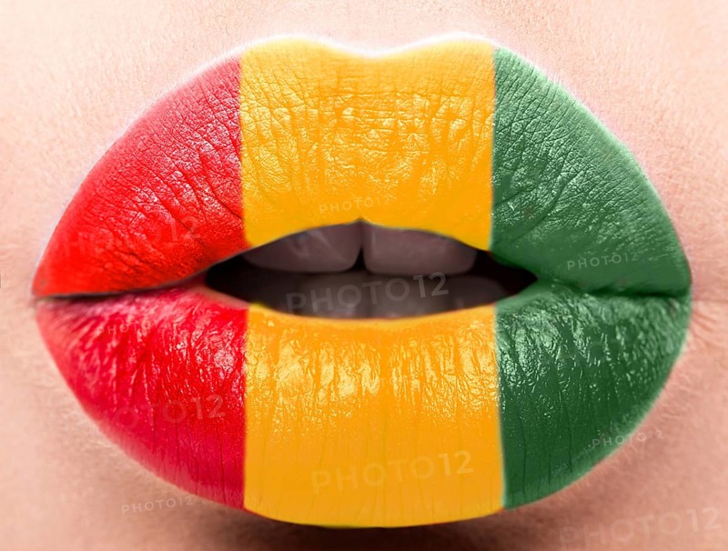 Female lips close up with a picture of the flag of Guinea. Yellow