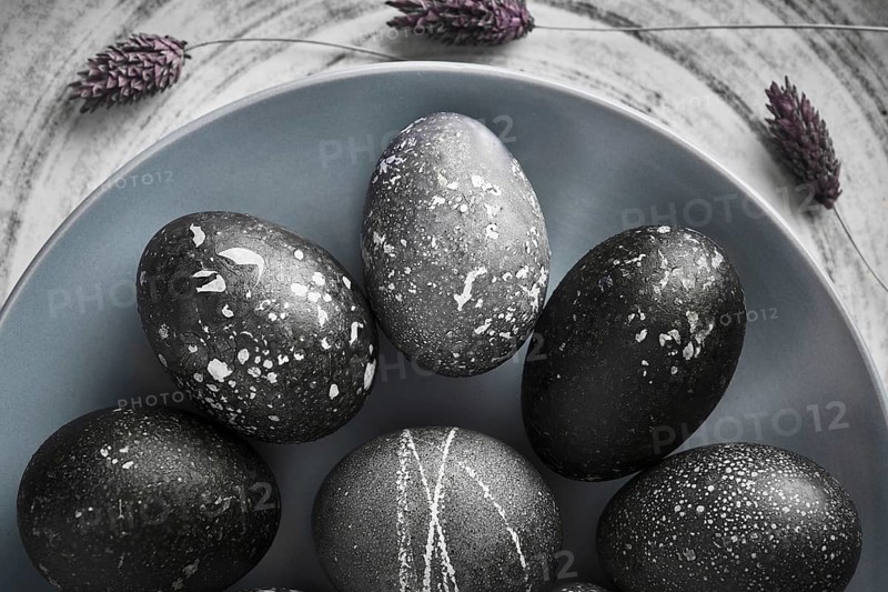 Black painted eggs for Easter on a blue plate