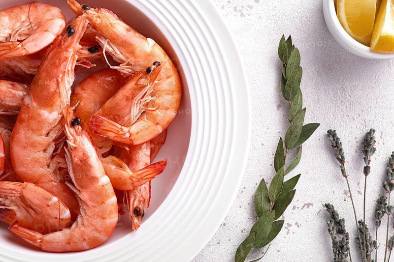 Boiled shrimps in a white plate with lemon