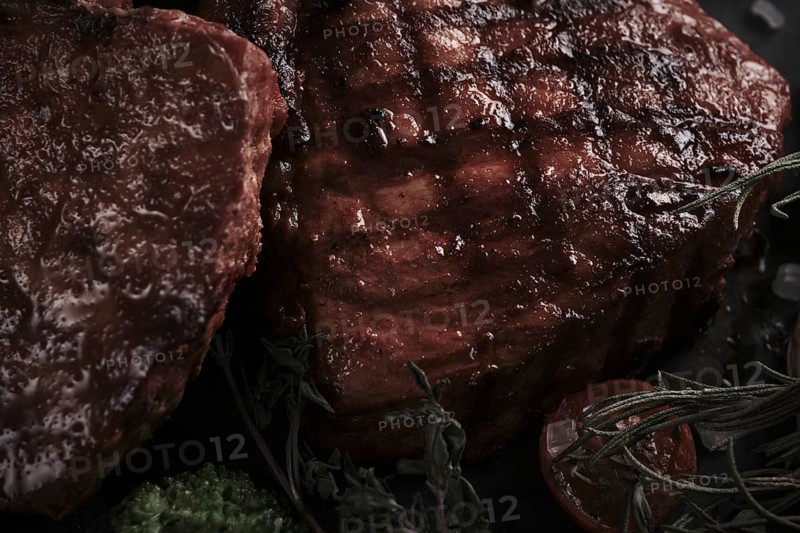 Piece of appetizing pork steak on the bone with vegetables in vintage style