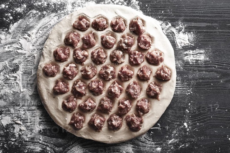 Handmade homemade dumplings on a metal tray on a wooden background with flour. Diy meat dumplings