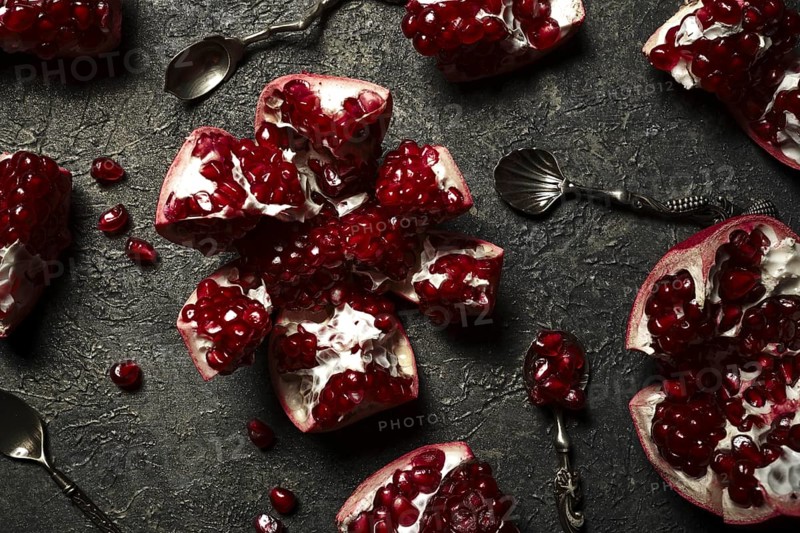 Metal background with pomegranate berries and retro spoons. Vintage style photo