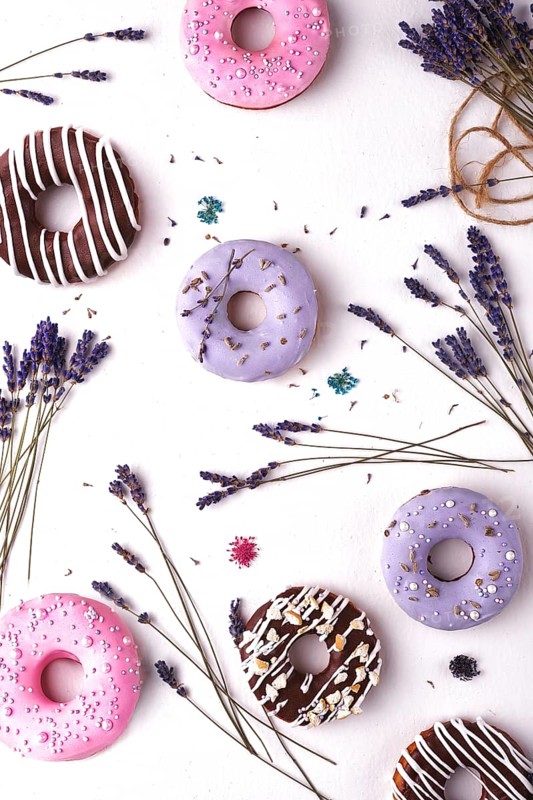 Sweet multicolored donuts on a white background with lavender flowers