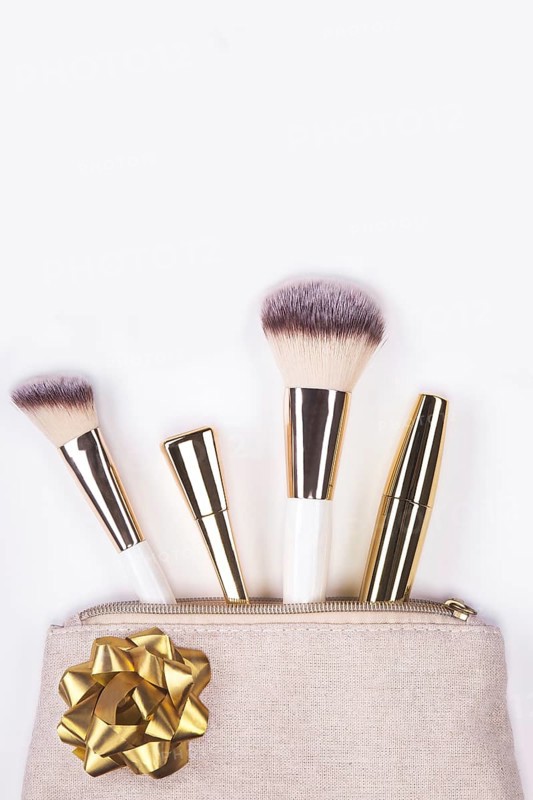 Set of brushes and cosmetic products in a cosmetic bag on a white background