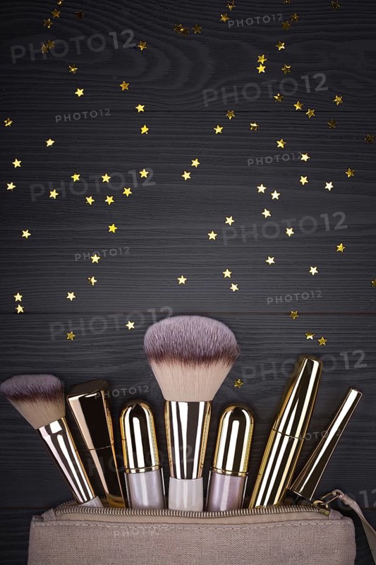 Set of brushes and cosmetic products in a cosmetic bag on a grey background