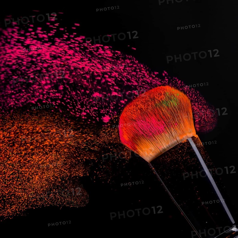 Cheek brush with neon cosmetic powder colorful spray and isolated on black background