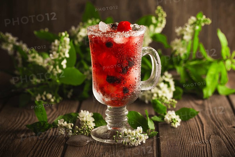Berry soft drink with ice on a wooden background with flowers