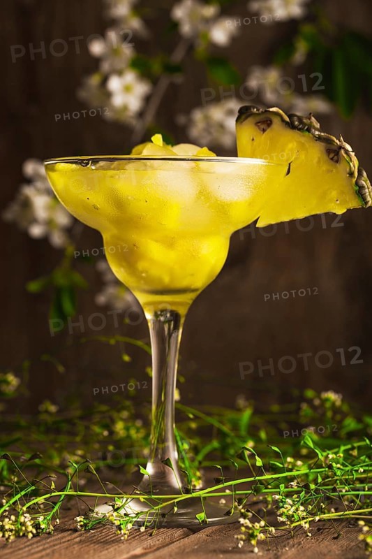 Pineapple fruit soft drink with ice on a wooden background with flowers