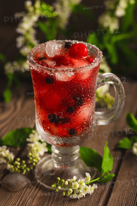 Berry soft drink with ice on a wooden background with flowers