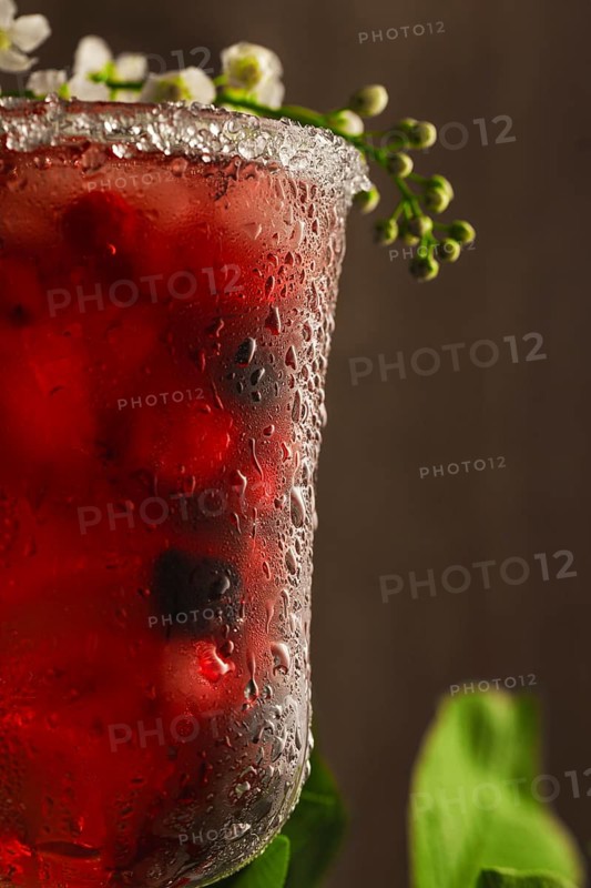 Berry soft drink with ice on a wooden background with flowers