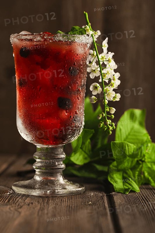 Berry soft drink with ice on a wooden background with flowers