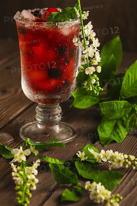 Berry soft drink with ice on a wooden background with flowers