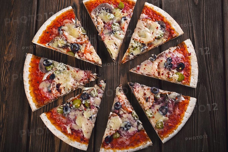 Sliced tasty fresh pizza with mushrooms and sausage on a wooden background. View from above. Close-up