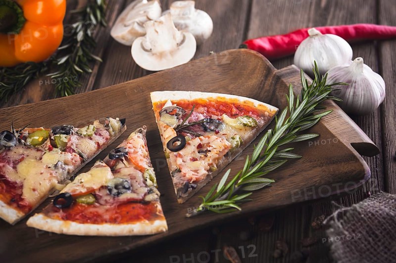 Sliced tasty fresh pizza with mushrooms and sausage on a wooden background. View from above. Close-up