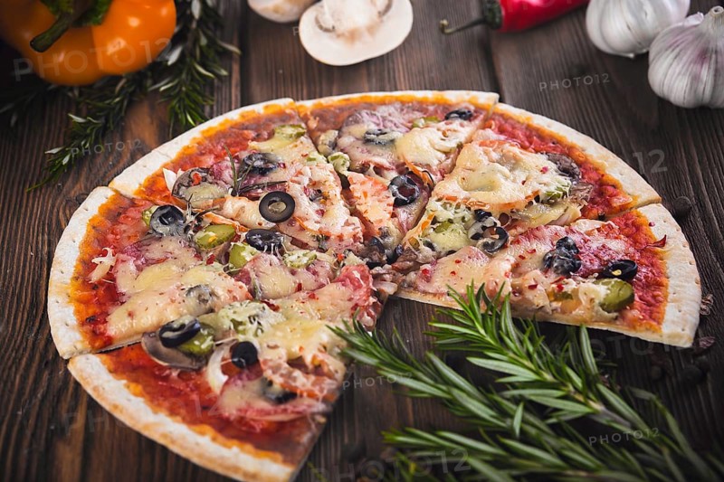 Sliced tasty fresh pizza with mushrooms and sausage on a wooden background. View from above. Close-up