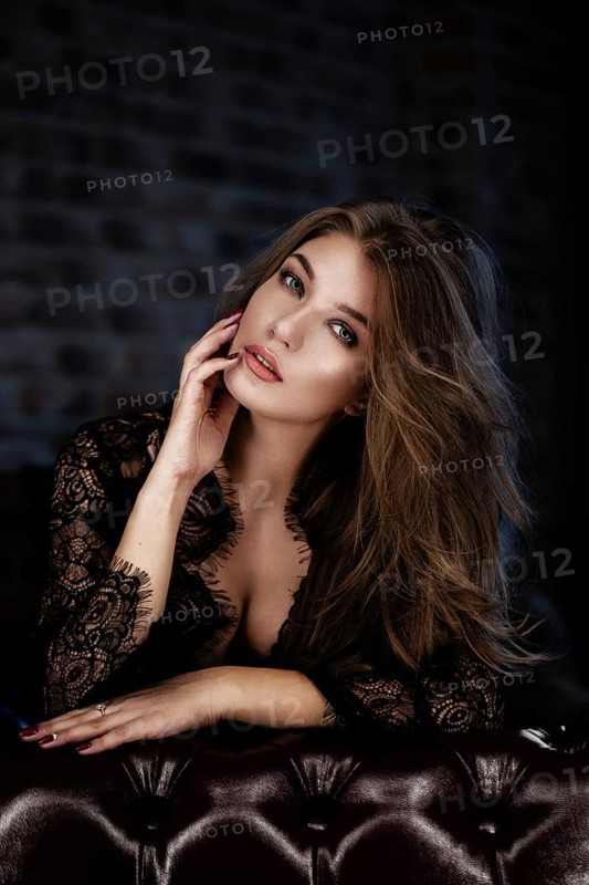 Beautiful sexy long-haired woman in black lingerie posing in the interior. The beauty of the face and body. Photos shot in a studio interior