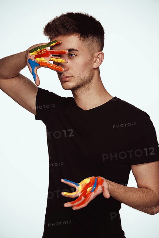 A young man with multi-colored paint on his hands. Hairdresser colorist or artist