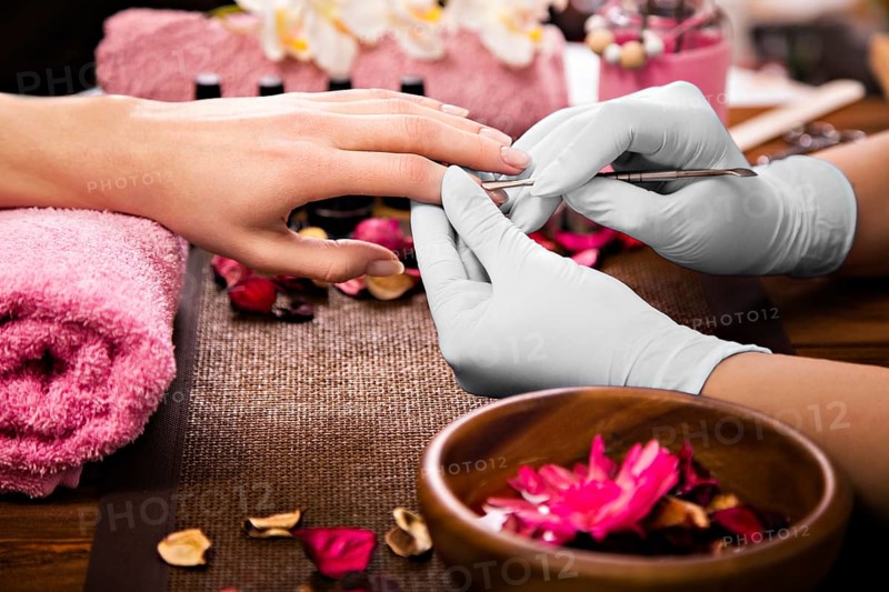 Closeup finger nail care by manicure specialist in beauty salon. Manicurist clear cuticle professional tool for manicure and pedicure