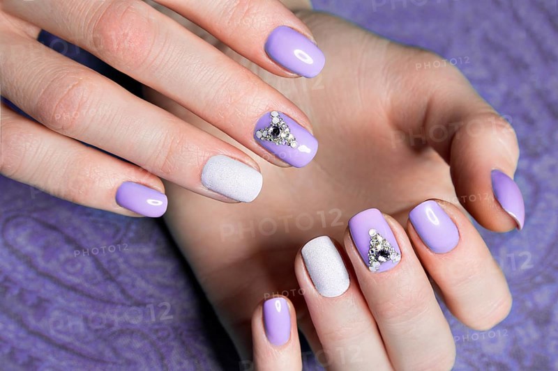 Beautiful purple manicure with crystals on female hand. Close-up. Picture taken in the studio