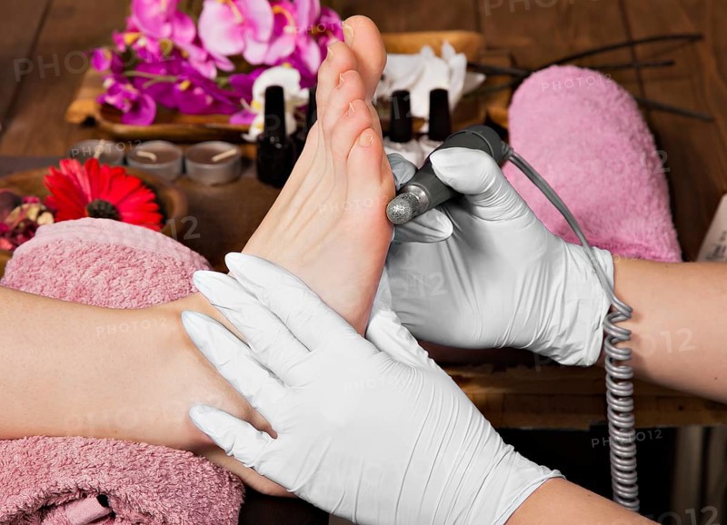 Closeup finger nail care by pedicure specialist in beauty salon. Pedicurist clear cuticle professional scissors for manicure and pedicure