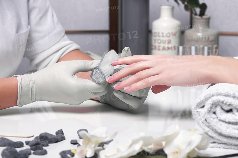 Closeup finger nail care by manicure specialist in beauty salon. Manicurist clear cuticle professional tool for manicure and pedicure