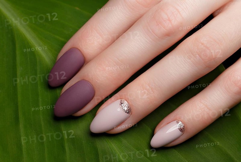 Tender neat manicure on female hands on a background of green leaves. Nail design
