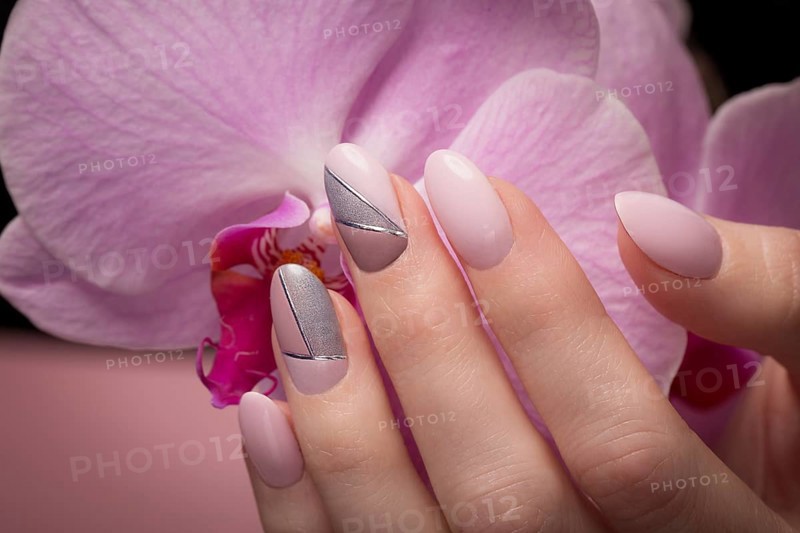 Purple neat manicure on female hands on a background of flowers. Nail design