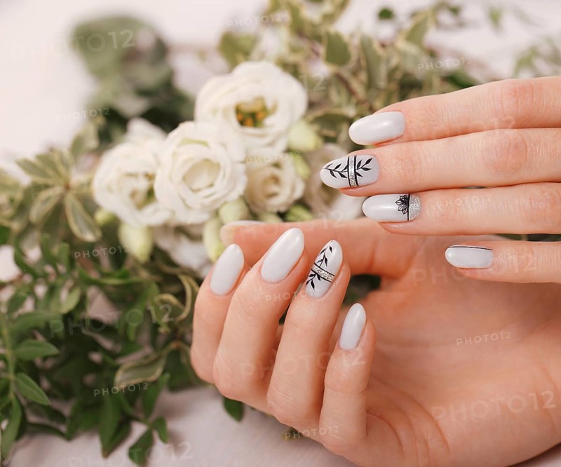 Gentle neat manicure on female hands on a background of flowers. Nail design