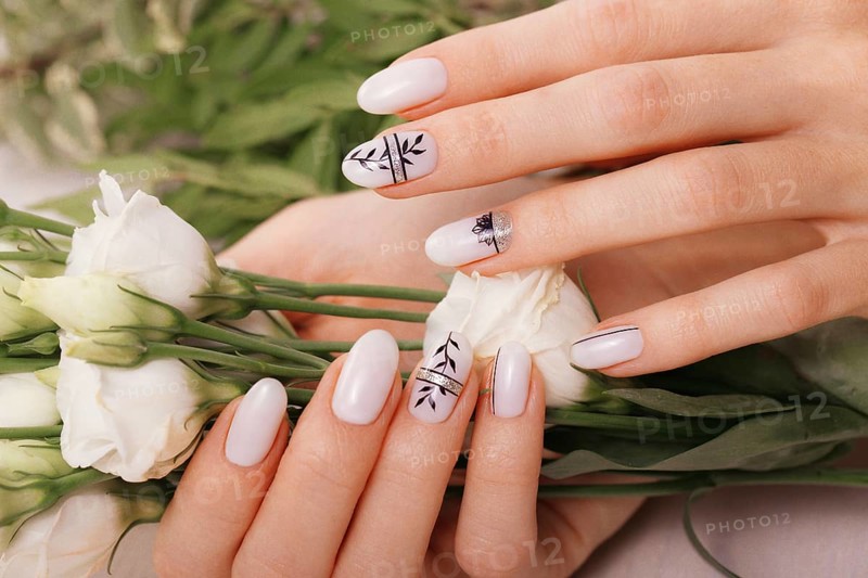 Gentle neat manicure on female hands on a background of flowers. Nail design
