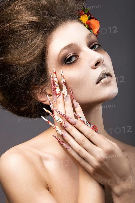 Beautiful girl in autumn image with long nails with bright and unusual make-up. Picture taken in the studio on a gray background