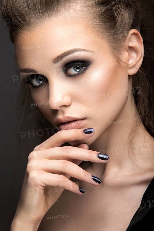 Beautiful girl in leather jacket with bright makeup and manicure Cat's Eye. Beauty face. Nail Design. Picture taken in the studio on a black background