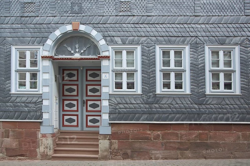 Historic house wall with door and window and slate shingles