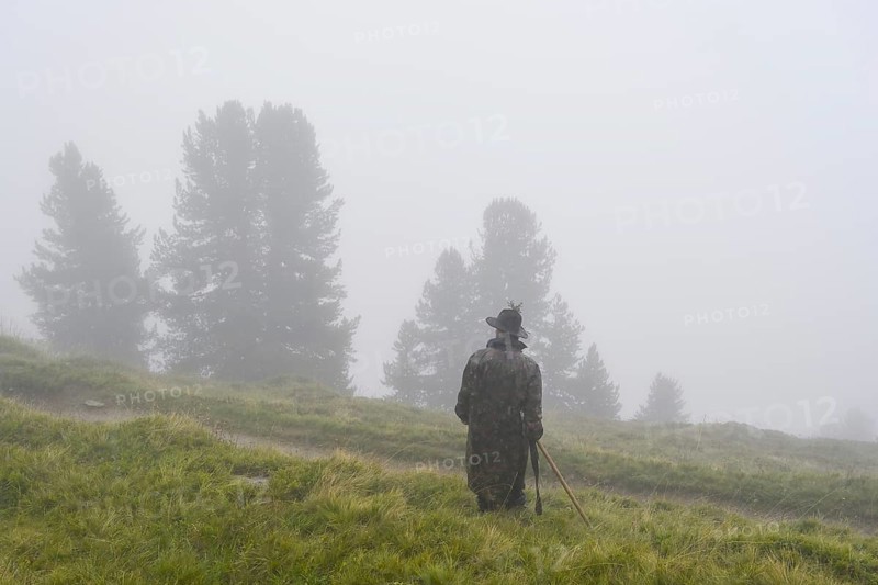 Shepherds standing on a meadow in the rain during the alpine migration