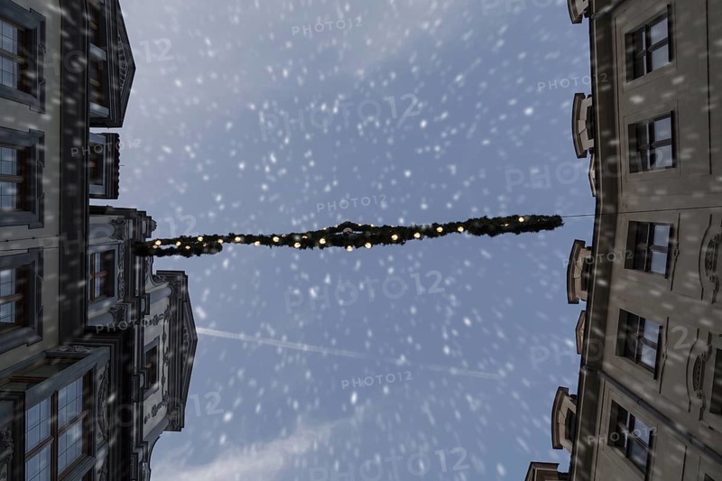 Christmas lights between two houses during snowfall