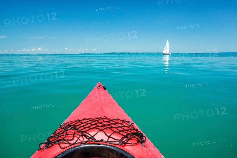 Bow of red kayak with view over the expanse and turquoise waters of Lake Constance